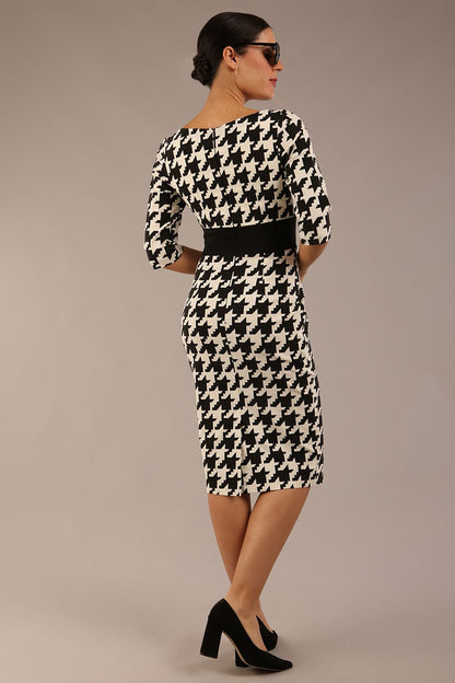 brunette model is wearing a diva catwalk OP-ART V-Neck Sleeved Monochrome Pencil Dress with black waistband and flower detail in a Super stretch dogtooth fabric black and white print front image