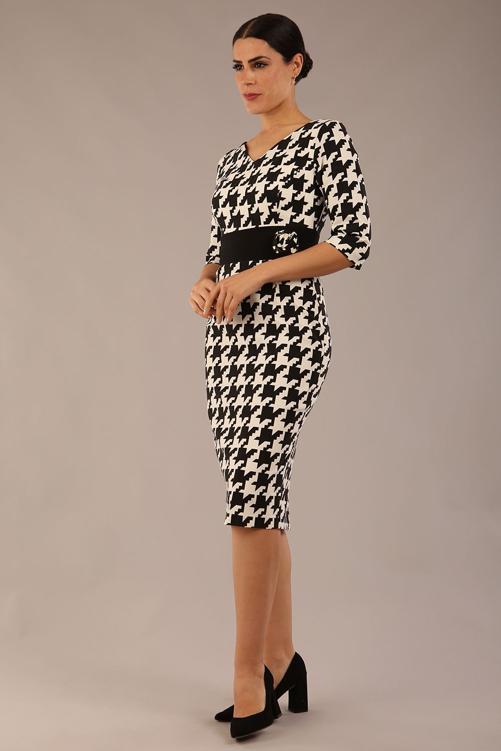 brunette model is wearing a diva catwalk OP-ART V-Neck Sleeved Monochrome Pencil Dress with black waistband and flower detail in a Super stretch dogtooth fabric black and white print front image