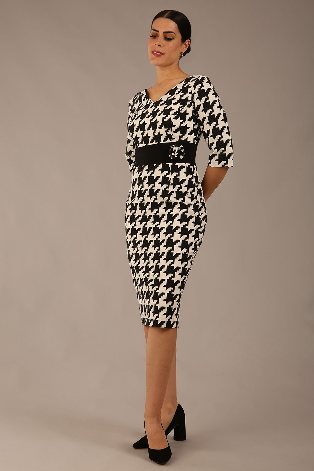 brunette model is wearing a diva catwalk OP-ART V-Neck Sleeved Monochrome Pencil Dress with black waistband and flower detail in a Super stretch dogtooth fabric black and white print front image