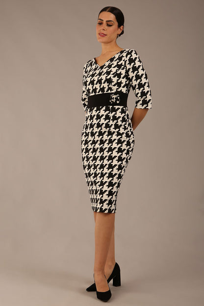 brunette model is wearing a diva catwalk OP-ART V-Neck Sleeved Monochrome Pencil Dress with black waistband and flower detail in a Super stretch dogtooth fabric black and white print front image