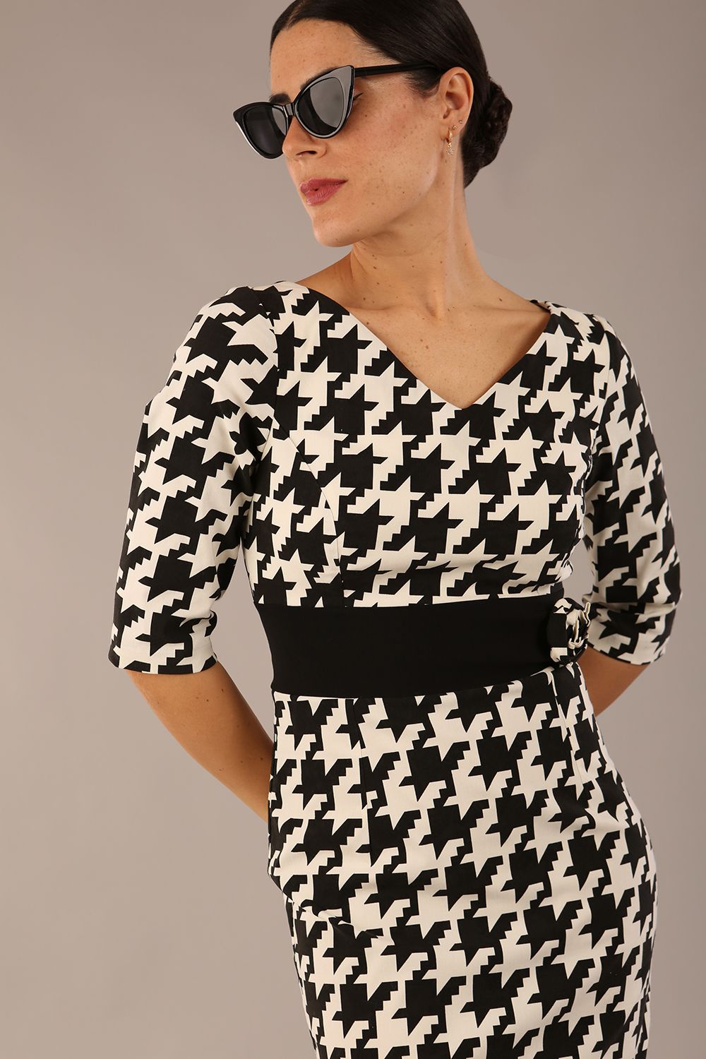 brunette model is wearing a diva catwalk OP-ART V-Neck Sleeved Monochrome Pencil Dress with black waistband and flower detail in a Super stretch dogtooth fabric black and white print front image