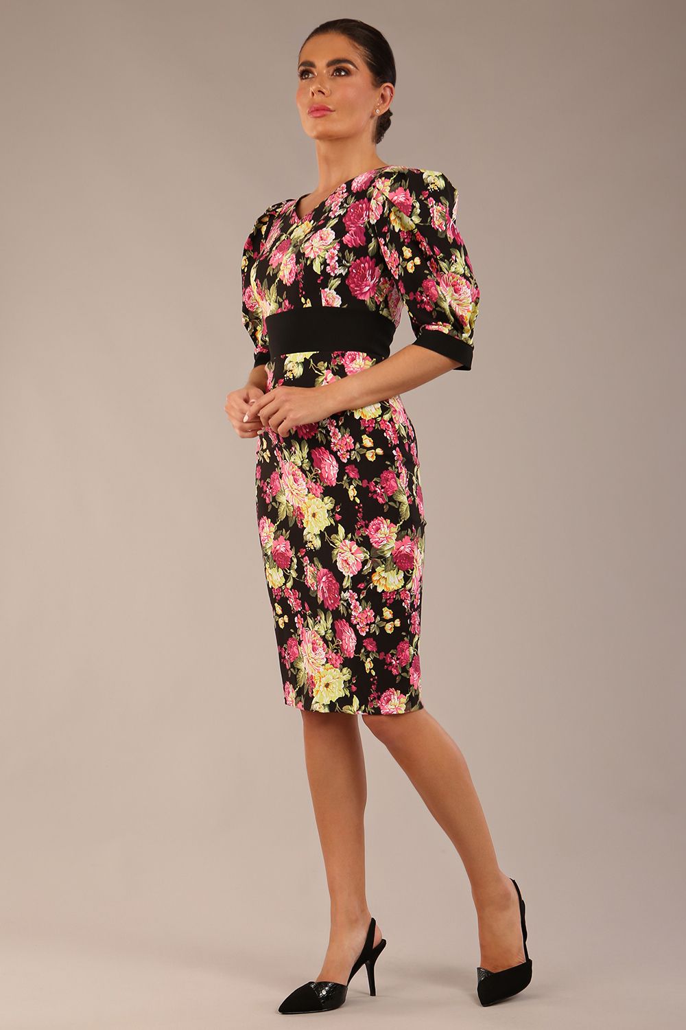 The brunette model is wearing a 7004 diva catwalk  Somerset Floral with Puff Sleeves & Black Waistband v neckline and knee length Pencil Dress in Black Spring Flower print front image