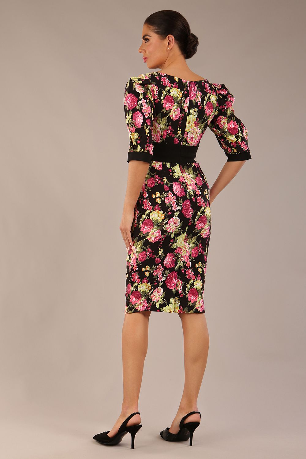 The brunette model is wearing a 7004 diva catwalk  Somerset Floral with Puff Sleeves & Black Waistband v neckline and knee length Pencil Dress in Black Spring Flower print back image