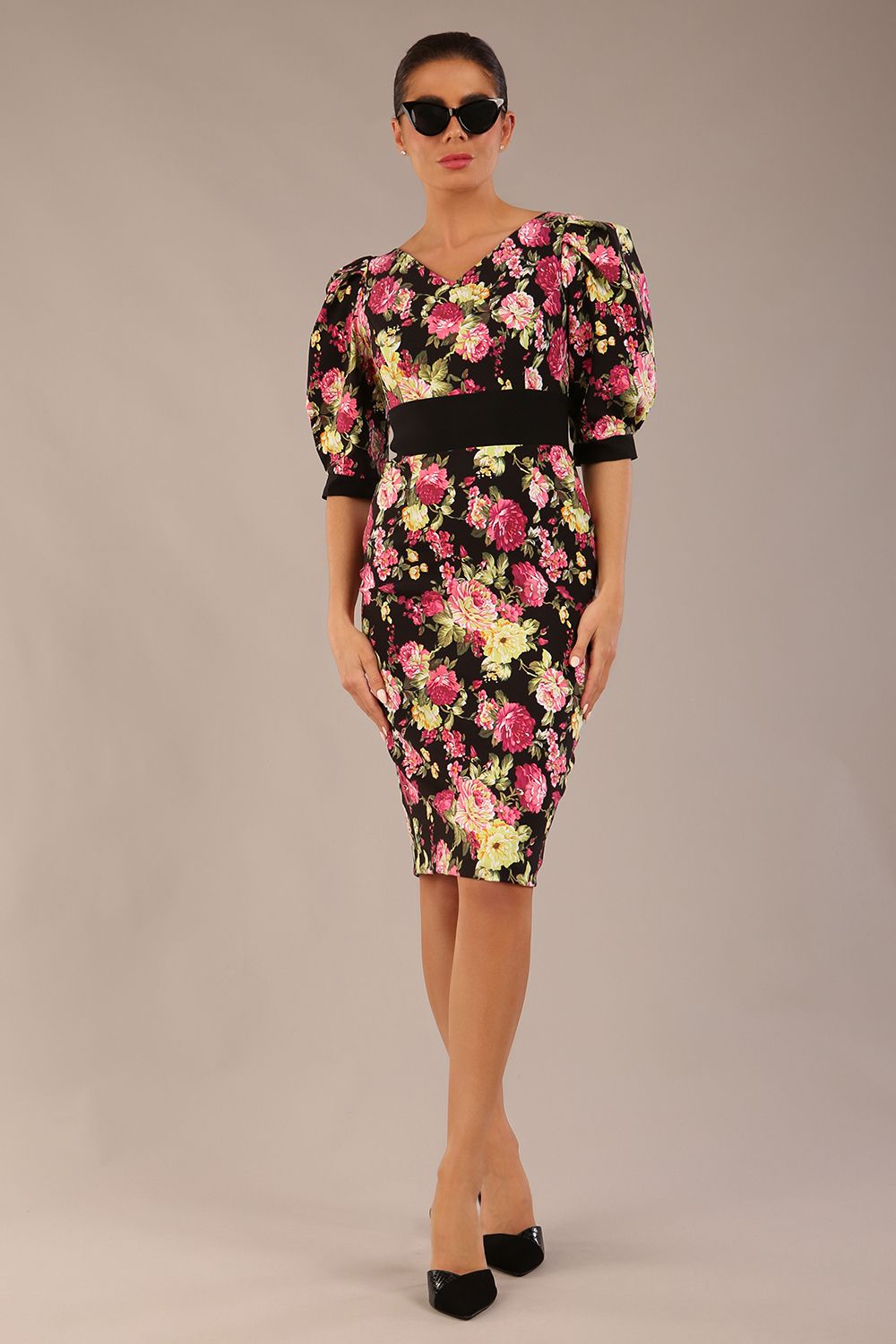 The brunette model is wearing a 7004 diva catwalk  Somerset Floral with Puff Sleeves & Black Waistband v neckline and knee length Pencil Dress in Black Spring Flower print front image
