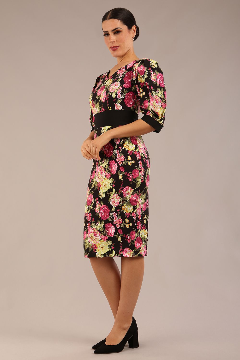 The brunette model is wearing a 7004 diva catwalk  Somerset Floral with Puff Sleeves & Black Waistband v neckline and knee length Pencil Dress in Black Spring Flower print front image