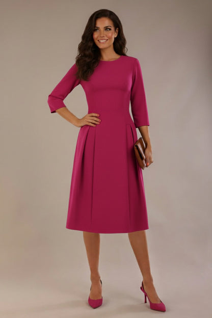Model wearing the Ario pleated A-line dress in festive fuchsia, showcasing the round neckline and 3/4 sleeves (Festive Fuchsia)