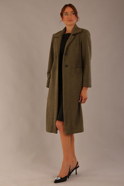 Model wearing the Ambrose boucle midi coat in olive green, long sleeves teddy feeling with a collar neckline and 2 closure buttons at the front and pockets (Olive Green)
