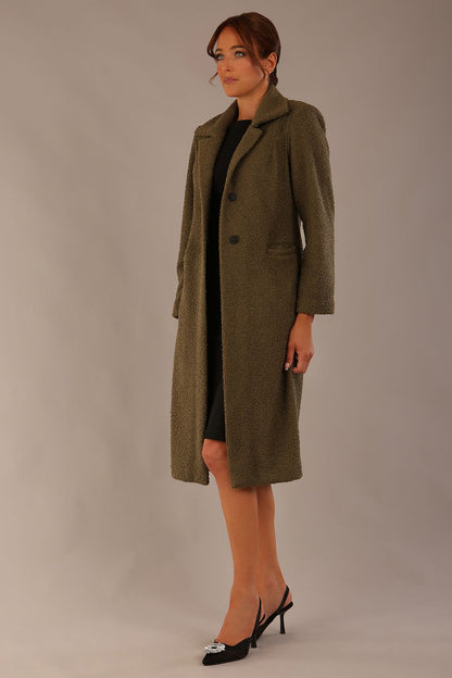 Model wearing the Ambrose boucle midi coat in olive green, long sleeves teddy feeling with a collar neckline and 2 closure buttons at the front and pockets (Olive Green)