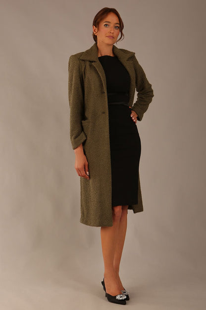 Model wearing the Ambrose boucle midi coat in olive green, long sleeves teddy feeling with a collar neckline and 2 closure buttons at the front and pockets (Olive Green)