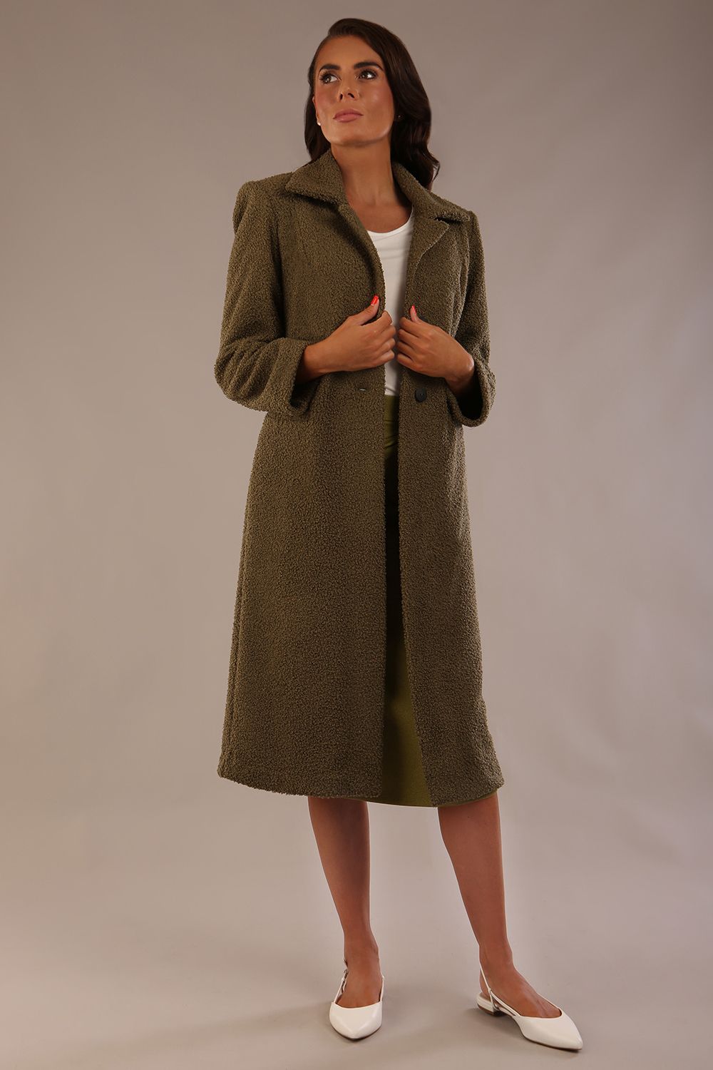 Model wearing the Ambrose boucle midi coat in olive green, long sleeves teddy feeling with a collar neckline and 2 closure buttons at the front and pockets (Olive Green)