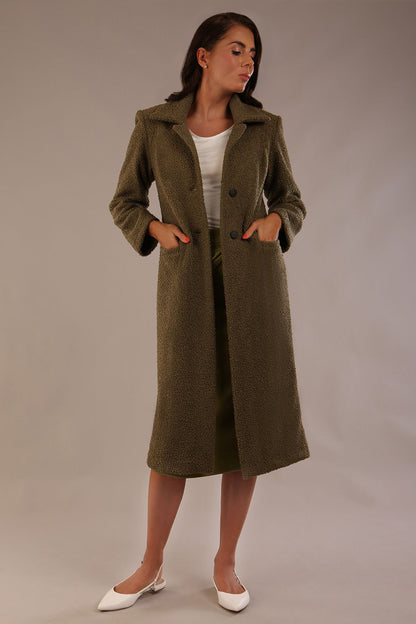 Model wearing the Ambrose boucle midi coat in olive green, long sleeves teddy feeling with a collar neckline and 2 closure buttons at the front and pockets (Olive Green)