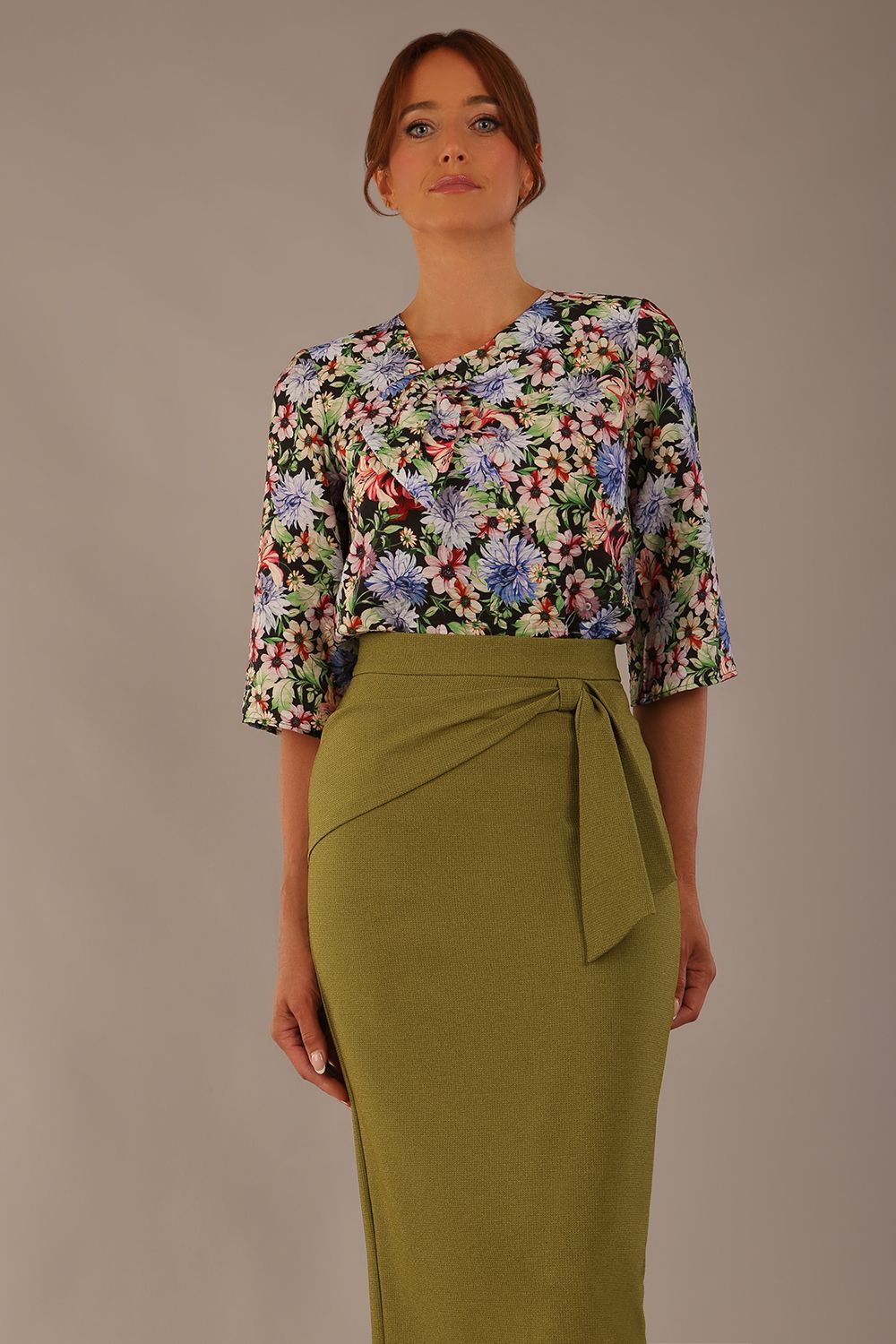 Model wearing a Suki asymmetric draped top in the Aurora Botanical print, styled with a olive green pencil skirt (Aurora Botanical)