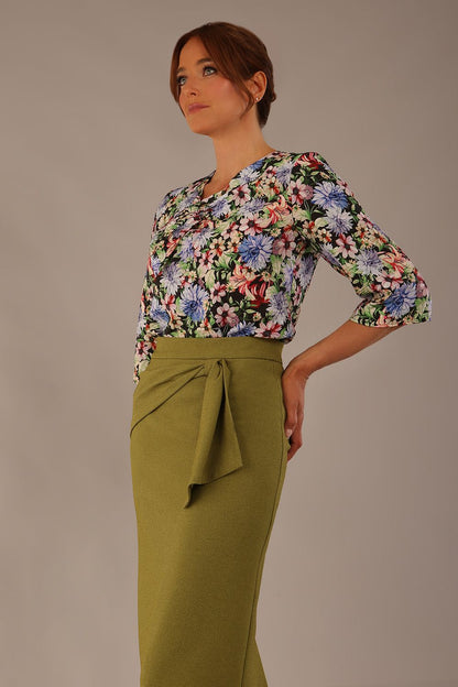 Model wearing a Suki asymmetric draped top in the Aurora Botanical print, styled with a olive green pencil skirt (Aurora Botanical)