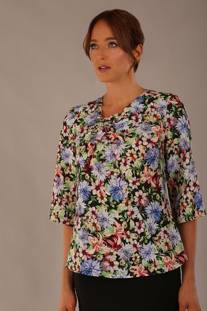 Model wearing a Suki asymmetric draped top in the Aurora Botanical print, styled with a olive green pencil skirt (Aurora Botanical)