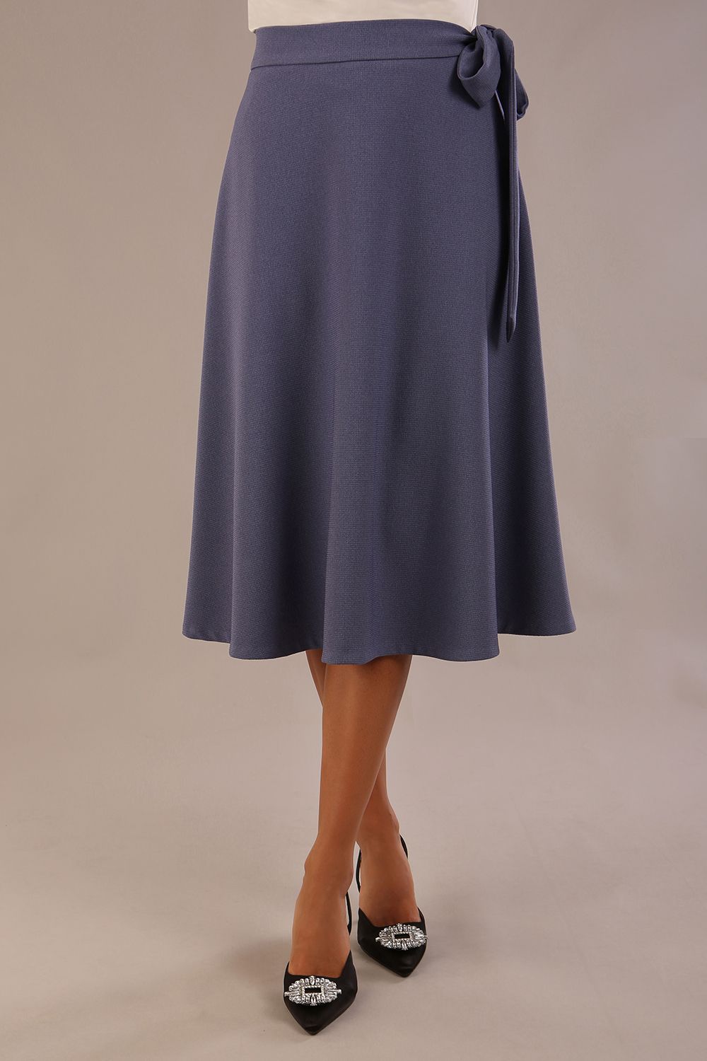 Model wearing the Harlow A-line midi skirt in blue mineral, with the side-tie fastened in a bow (Blue Mineral)