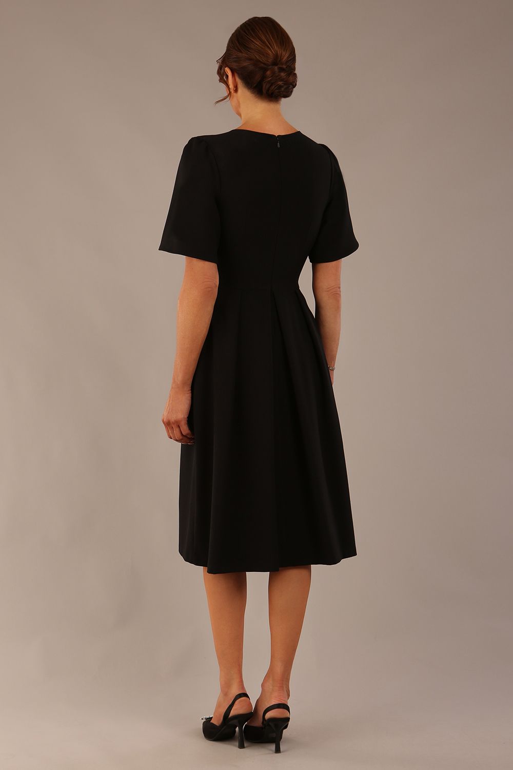 Close-up of the Model wearing the Dale pleated A-line dress against a plain background (Black)