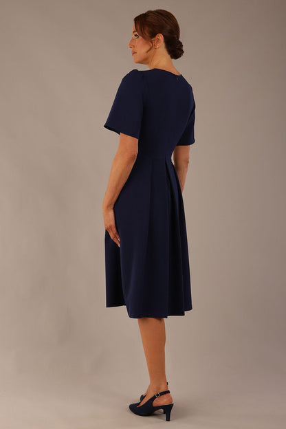 Model wearing the Dale pleated A-line dress against a plain background (Navy Blue)