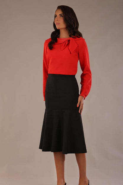 model wearing a Cressida long sleeve top in poppy red, with a boat neckline and asymmetric bow, styled with a pencil skirt close up (Poppy Red)