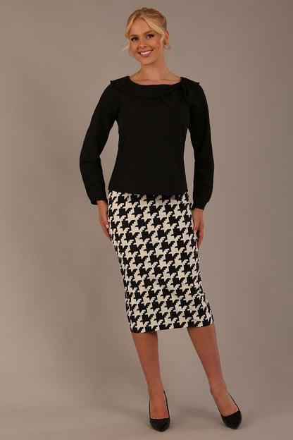 Woman sitting on a chair wearing a diva catwalk cressida black top and houndstooth-patterned skirt against a plain background (Houndstooth print)