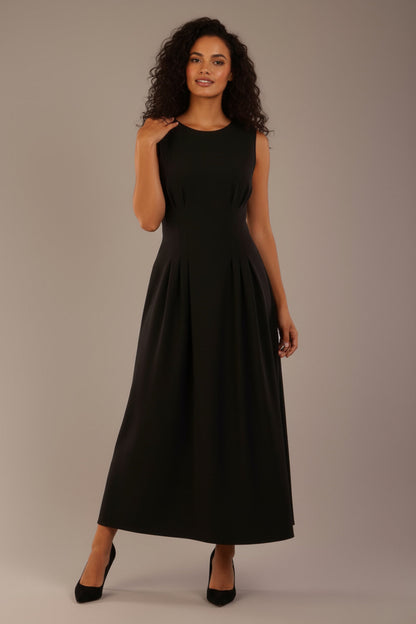Model wearing the Cleo pleated midaxi dress in black with hands in the discreet side pockets (Black)