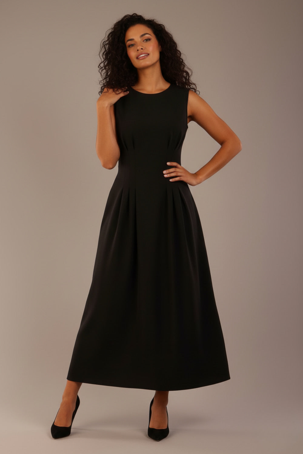 Model wearing the Cleo pleated midaxi dress in black with hands in the discreet side pockets (Black)