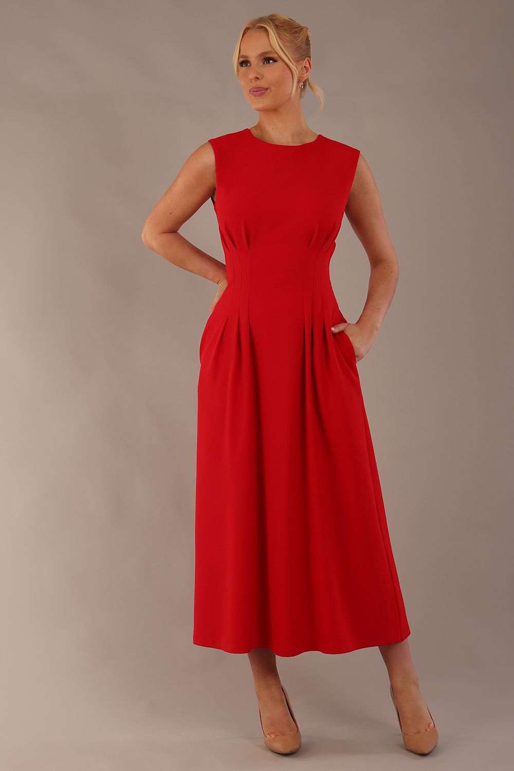Model wearing the Cleo pleated midaxi dress in scarlet red with hands in the discreet side pockets (Scarlet Red)