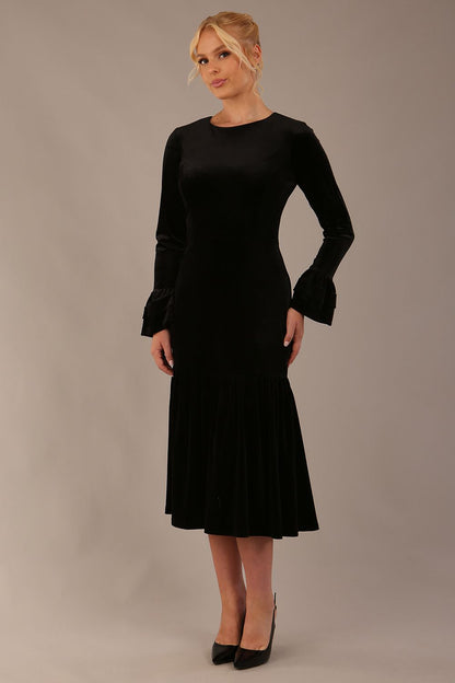 Model wearing the Sophisticat fluted sleeve velvet dress in black (Black Velvet)