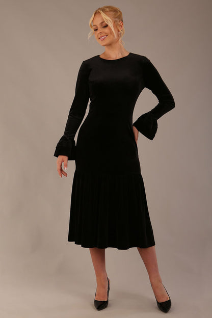 Model wearing the Sophisticat fluted sleeve velvet dress in black (Black Velvet)