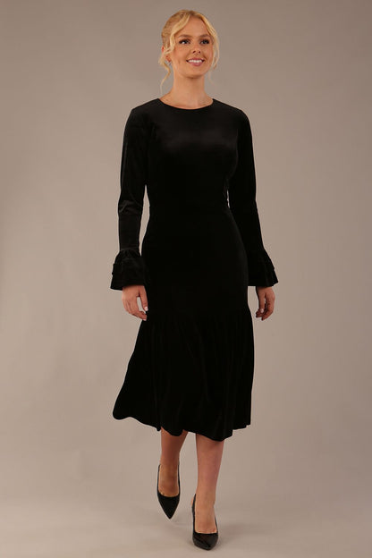Model wearing the Sophisticat fluted sleeve velvet dress in black (Black Velvet)