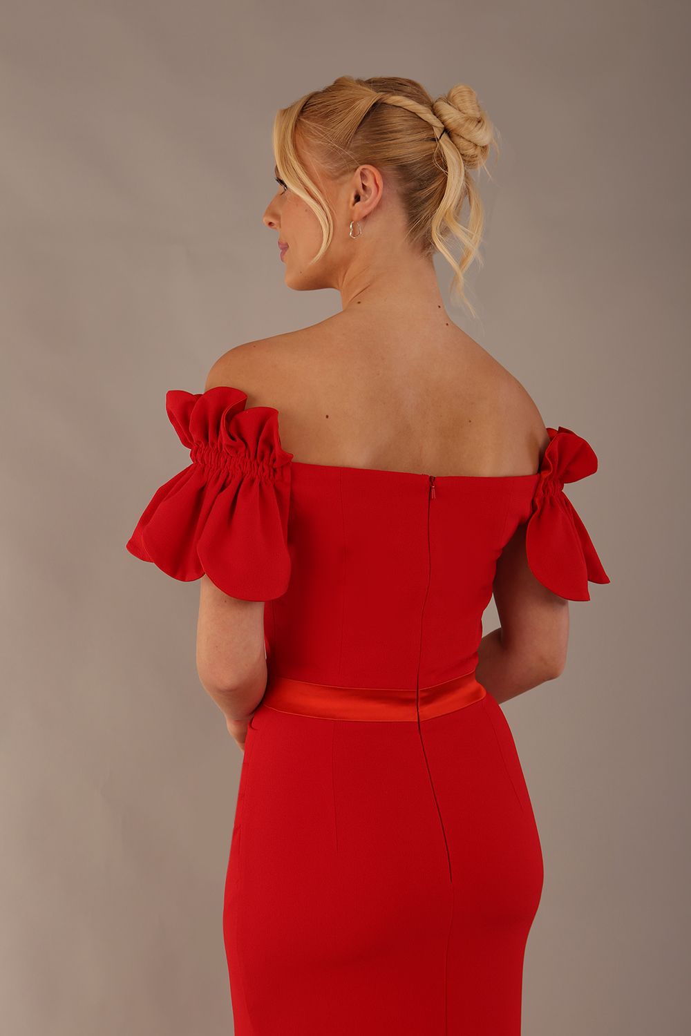 Woman wearing a red dress with ruffled sleeves in an elegant indoor setting. (Passion Red & Fire Orange Satin)