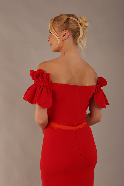Woman wearing a red dress with ruffled sleeves in an elegant indoor setting. (Passion Red & Fire Orange Satin)