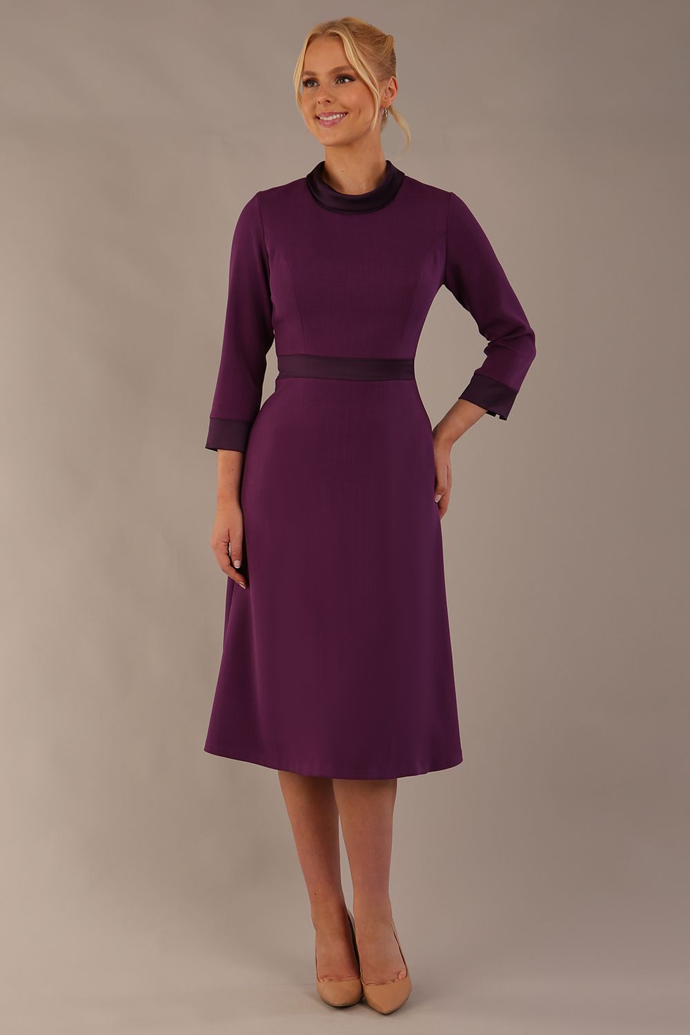 Model wearing the Sybil A-line midi dress in imperial purple with a satin cowl neck and waistband. (Imperial Purple)