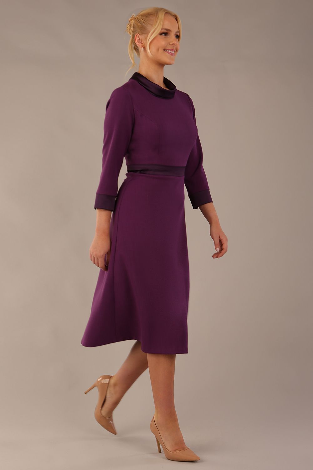 Model wearing the Sybil A-line midi dress in imperial purple with a satin cowl neck and waistband. (Imperial Purple)