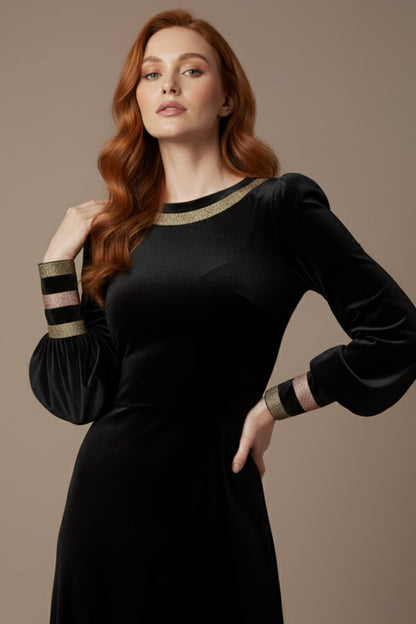 Woman wearing a black dress with gold accents sitting on a stool against a beige background (Black Velvet with Sherwood Glitter Contrast)