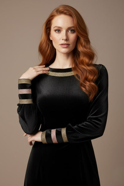 Woman wearing a black dress with gold accents sitting on a stool against a beige background (Black Velvet with Sherwood Glitter Contrast)