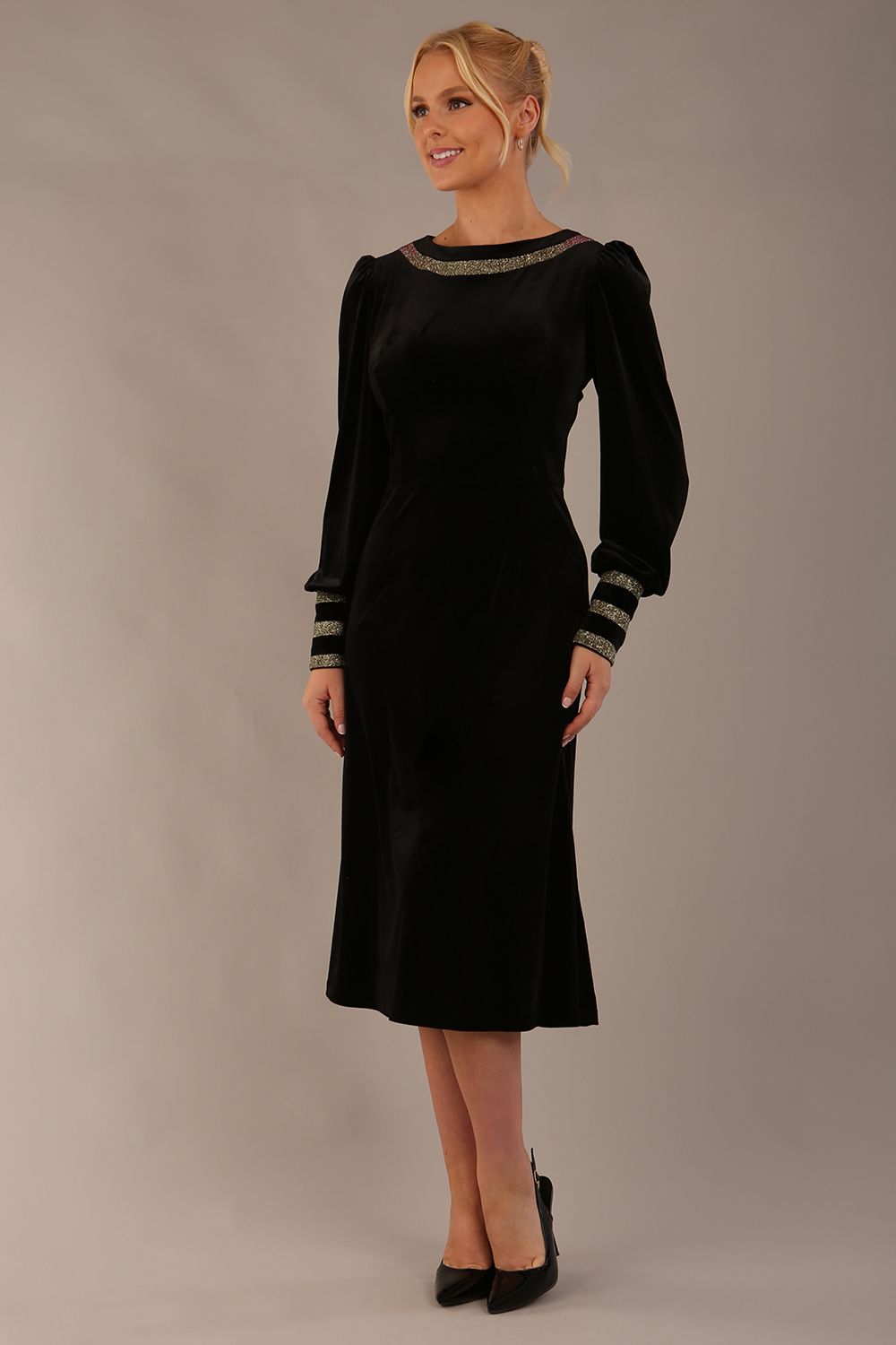 Woman wearing a black dress with gold accents sitting on a stool against a beige background (Black Velvet with Sherwood Glitter Contrast)