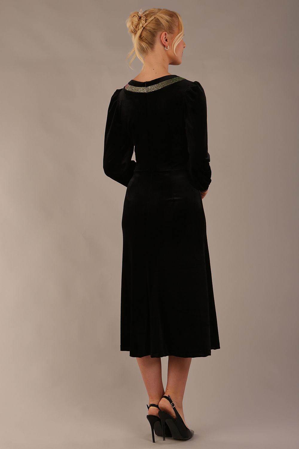 Woman wearing a black dress with gold accents sitting on a stool against a beige background (Black Velvet with Sherwood Glitter Contrast)