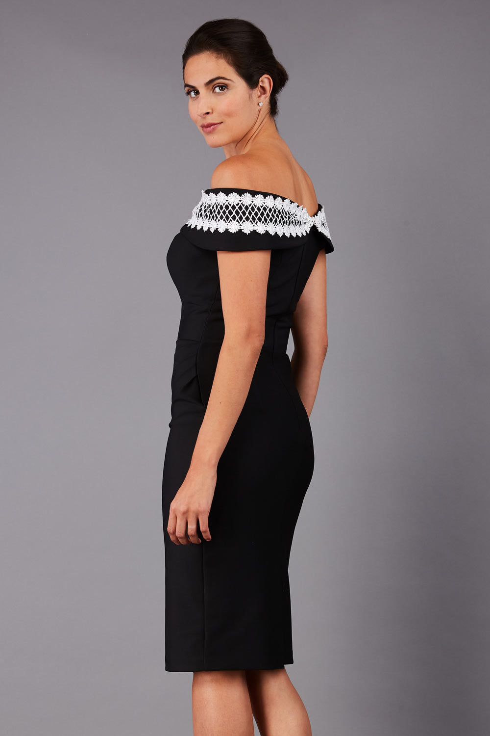 brunette model wearing diva catwalk kurumba pencil dress with bardot off shoulder neckline and lace detail across it in black and white colour front