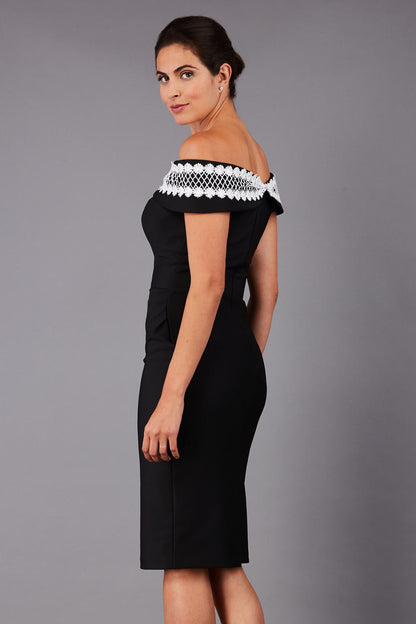 brunette model wearing diva catwalk kurumba pencil dress with bardot off shoulder neckline and lace detail across it in black and white colour front