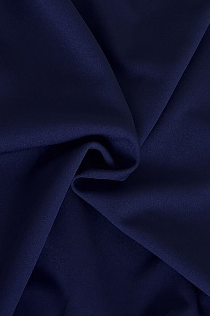 Woman in a navy blue dress standing in an elegant room with a mirror and decor. (Navy Blue)