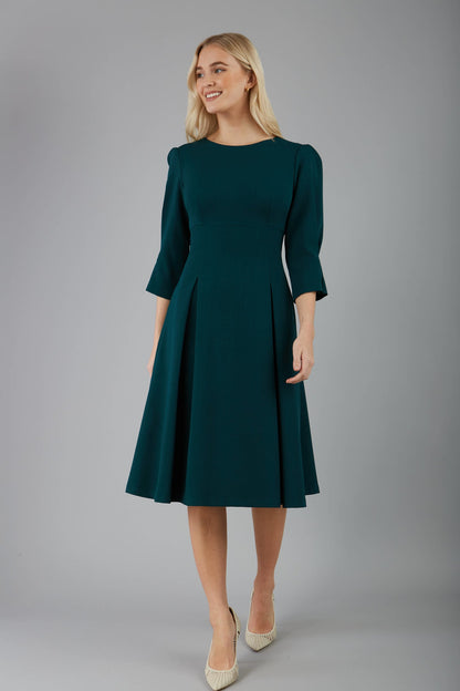 blonde model is wearing diva catwalk harpsden a-line skirt 3/4 sleeve swing dress with rounded neckline in forest green front