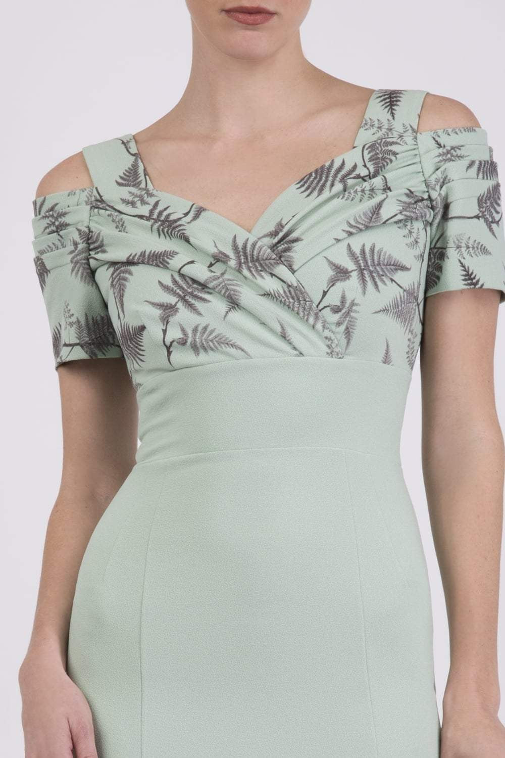 Woman wearing a light green dress with a patterned top and plain skirt against a brown background (Deco Green Fern)