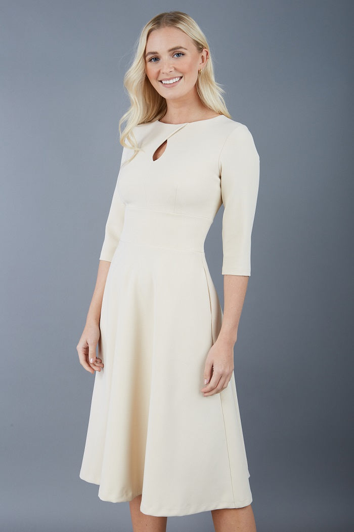 model is wearing diva catwalk casares swing dress with a keyhole neckline three quarter sleeve dress with pocket detail in Sandshell Beige front (Sandshell Beige)