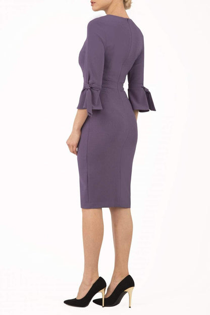 blonde model wearing diva catwalk zoe 3 4 sleeve formal dress with a split rounded neckline and split on skirt in opulent mauve front
