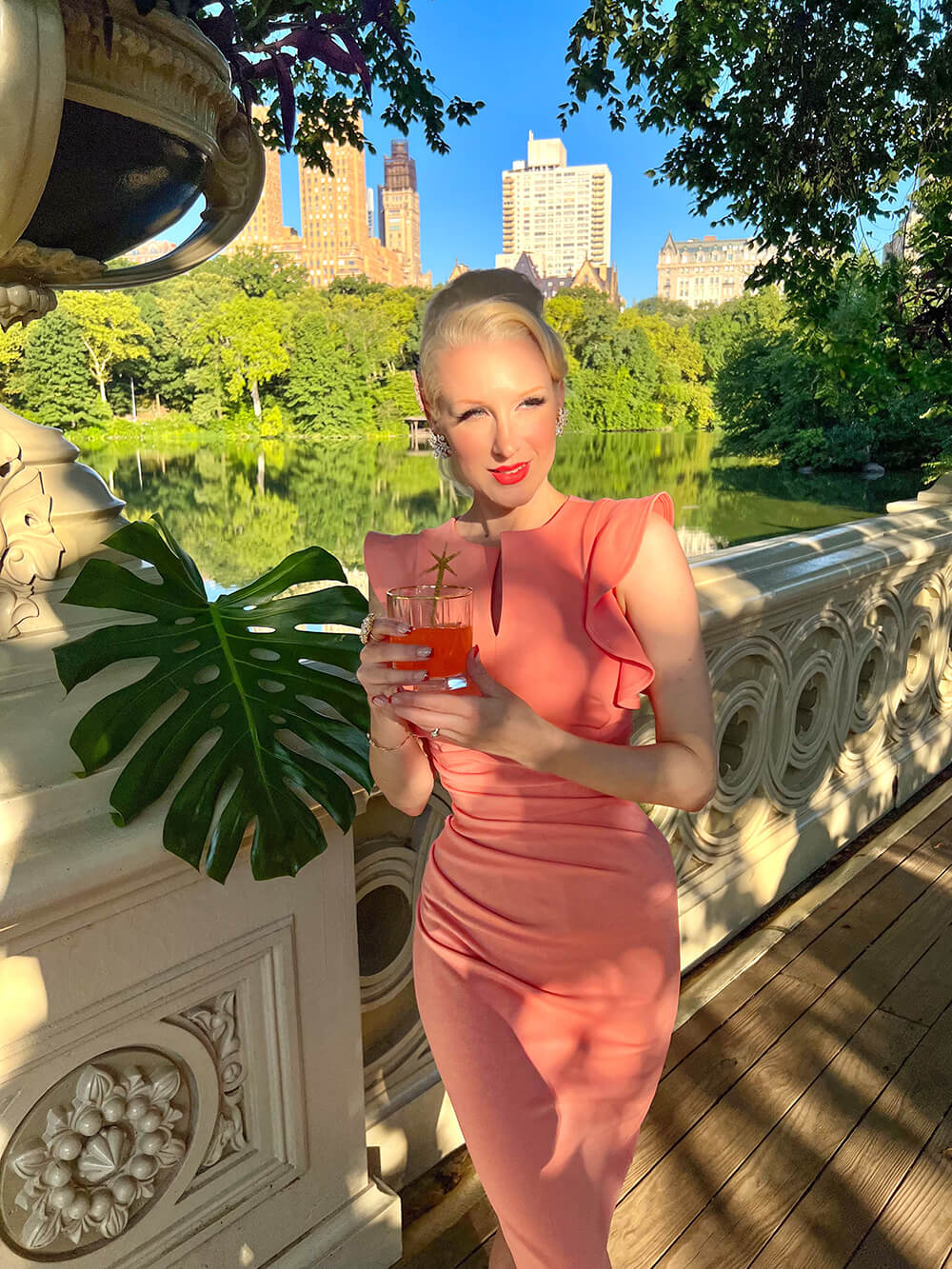 model wearing diva catwalk Bodiam Bodycon Pencil Dress with frill sleeves in knee length and pleating across the tummy in peach front (Tropical Peach)