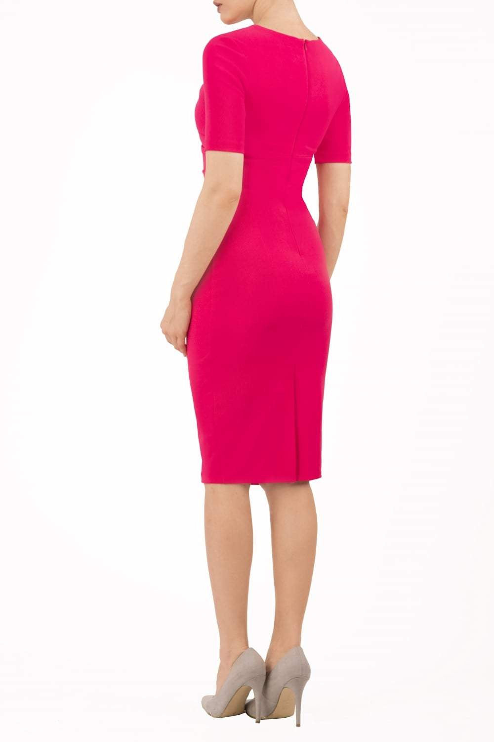 blonde model is wearing diva catwalk lydia short sleeve pencil fitted dress in paradise pink colour with rounded neckline with a slit in the middle front fusia pink