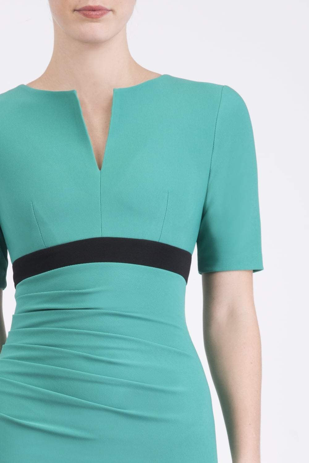brunette model wearing diva catwalk nadia fitted dress with pencil pleated skirt with sleeves and rounded neckline with split in colour emerald green front