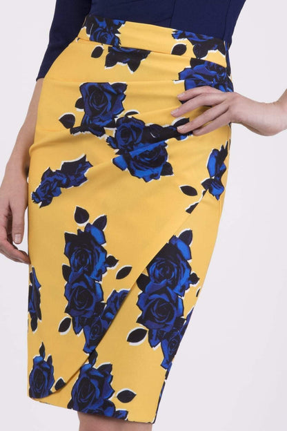 Woman wearing a navy top and yellow floral skirt on a city street.