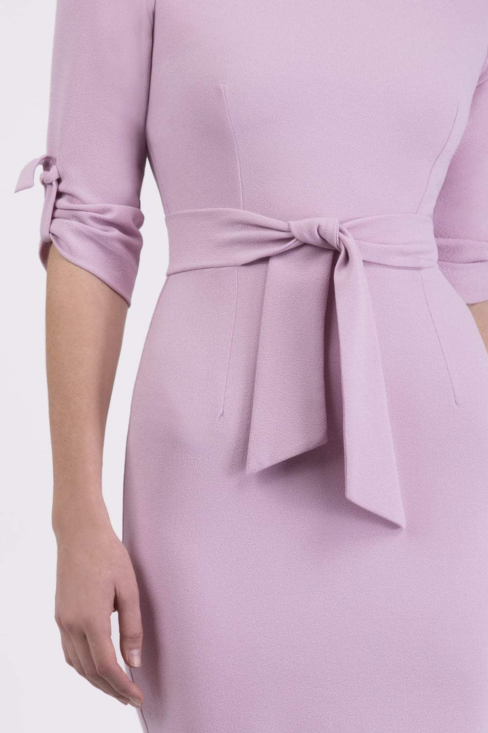brunette model wearing diva catwalk tryst pencil dawn pink dress with sleeves and belt detail at the front with rounded neckline front